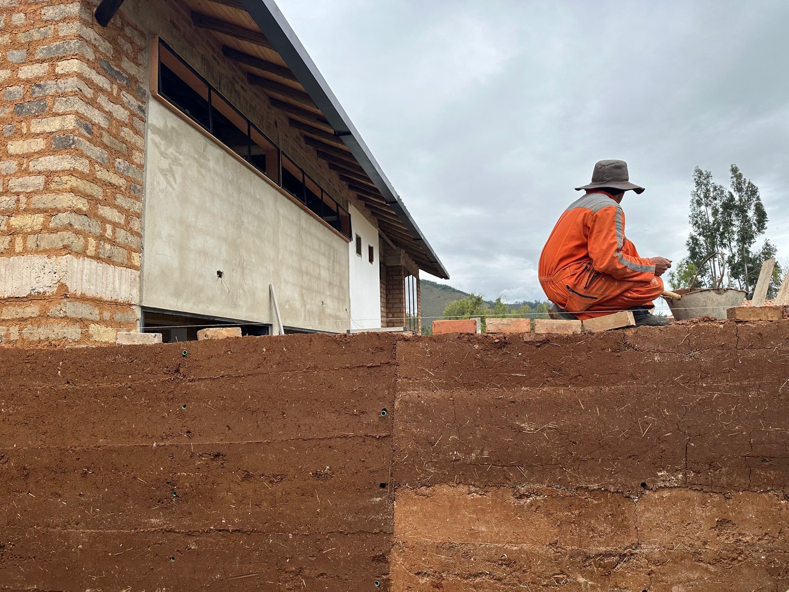 Maestro de obra levantando un muro sobre una base en tierra apisonada
